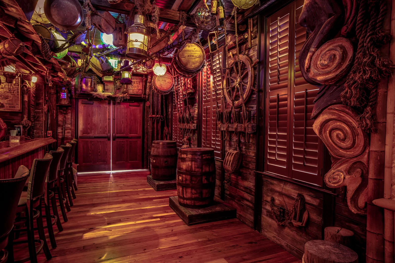 The Bamboo Room bar area with warm red and amber lighting and tiki carvings