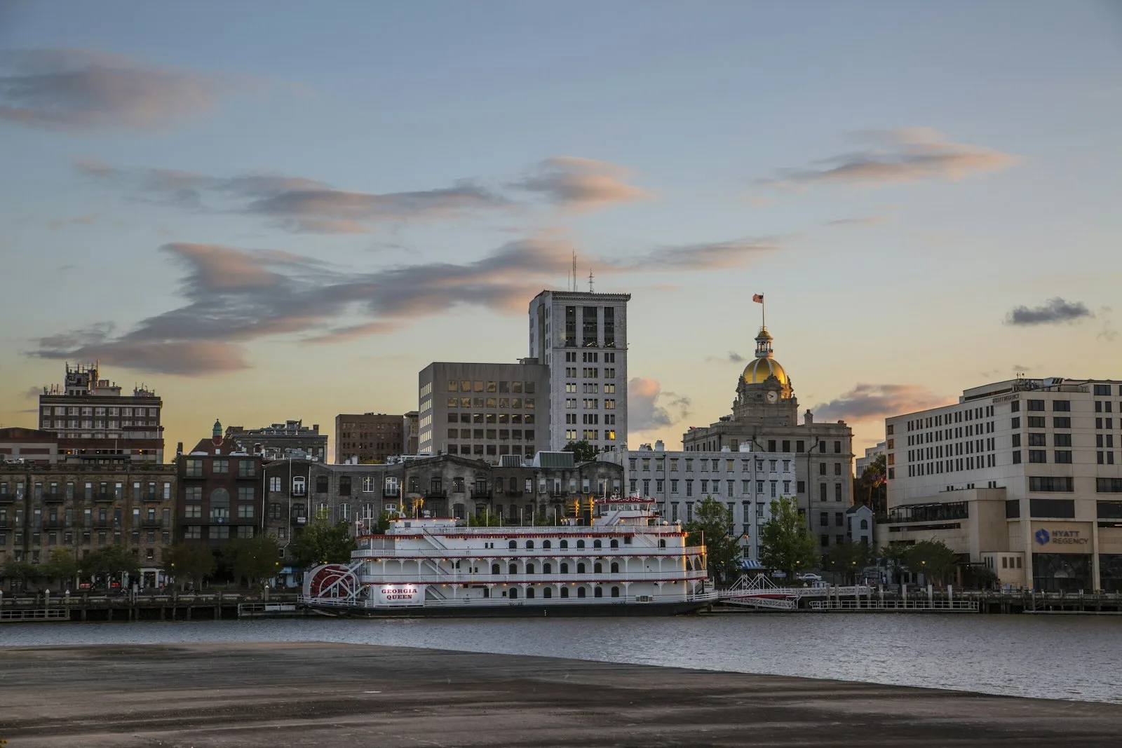 Savannah riverfront at dusk with the Georgia Queen paddleboat and City Hall gold dome